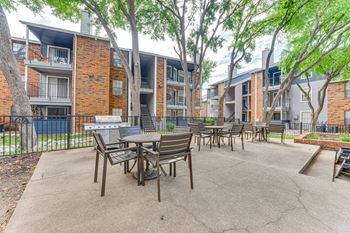 A patio with a table and chairs is surrounded by apartment buildings.